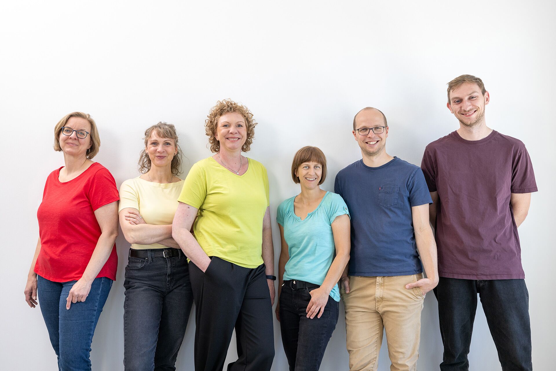 designerei-Mitarbeiter lehnen locker, lächelnd  an weißer Wand