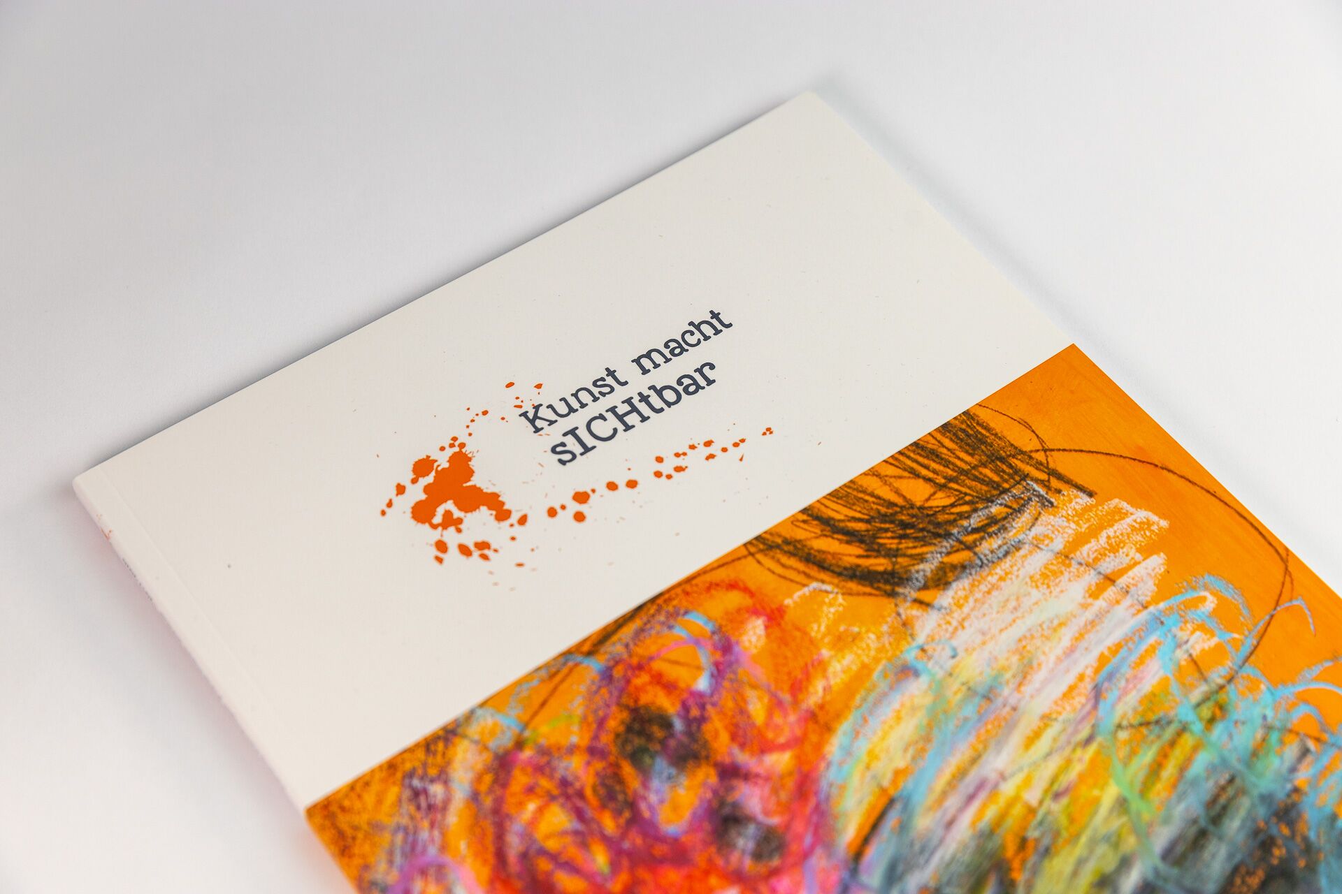 Katalogdesign: Titel des Ausstellungskatalogs Kunst macht sichtbar mit einem abstrakten Bild in bunten Farben
