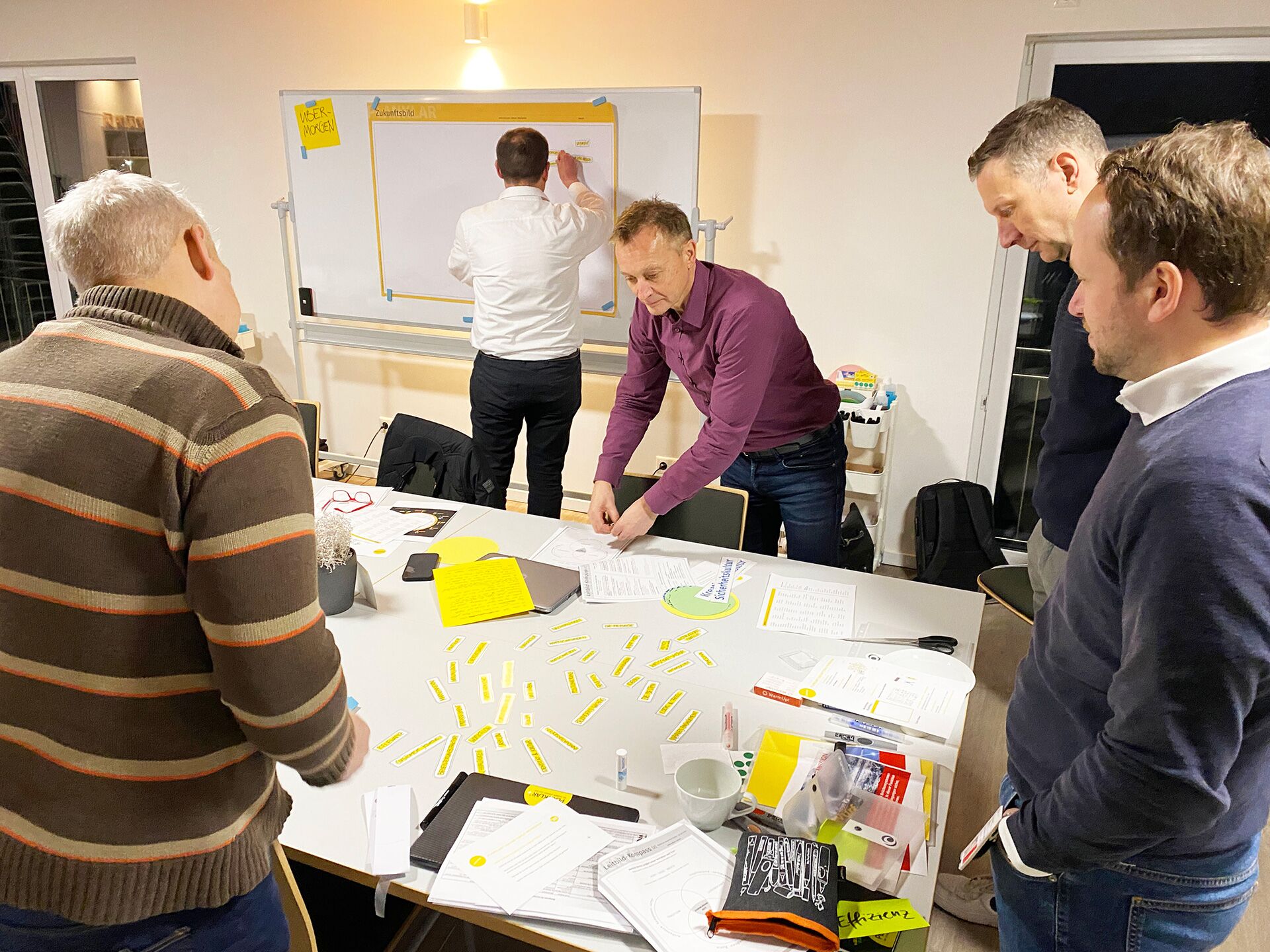 Unternehmenskultur entwickeln: Teilnehmer arbeiten im Workshop an Tisch mit bunten Moderationsmaterialen