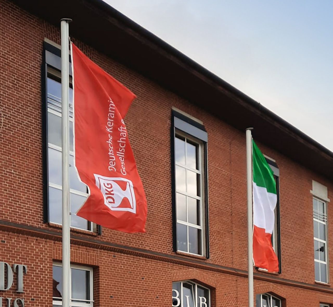 rote Werbefahne mit weißem DKG-Logo zur CERAMICS 2023 vor dem Stadthaus Hermsdorf