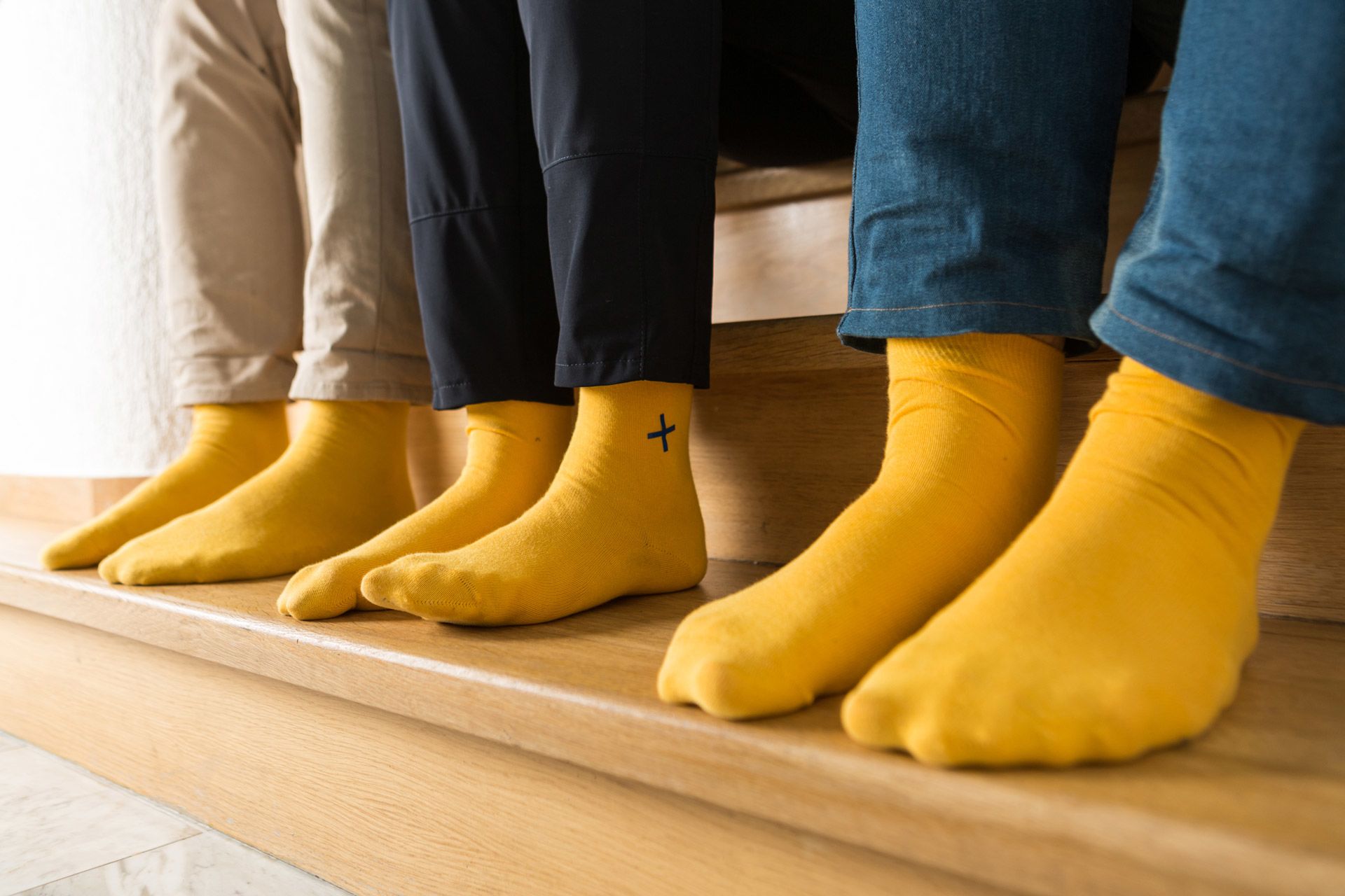 Nahaufnahme der designerei yellow socks mit blauem Plus – das Markenzeichen der designerei-Werbeagentur