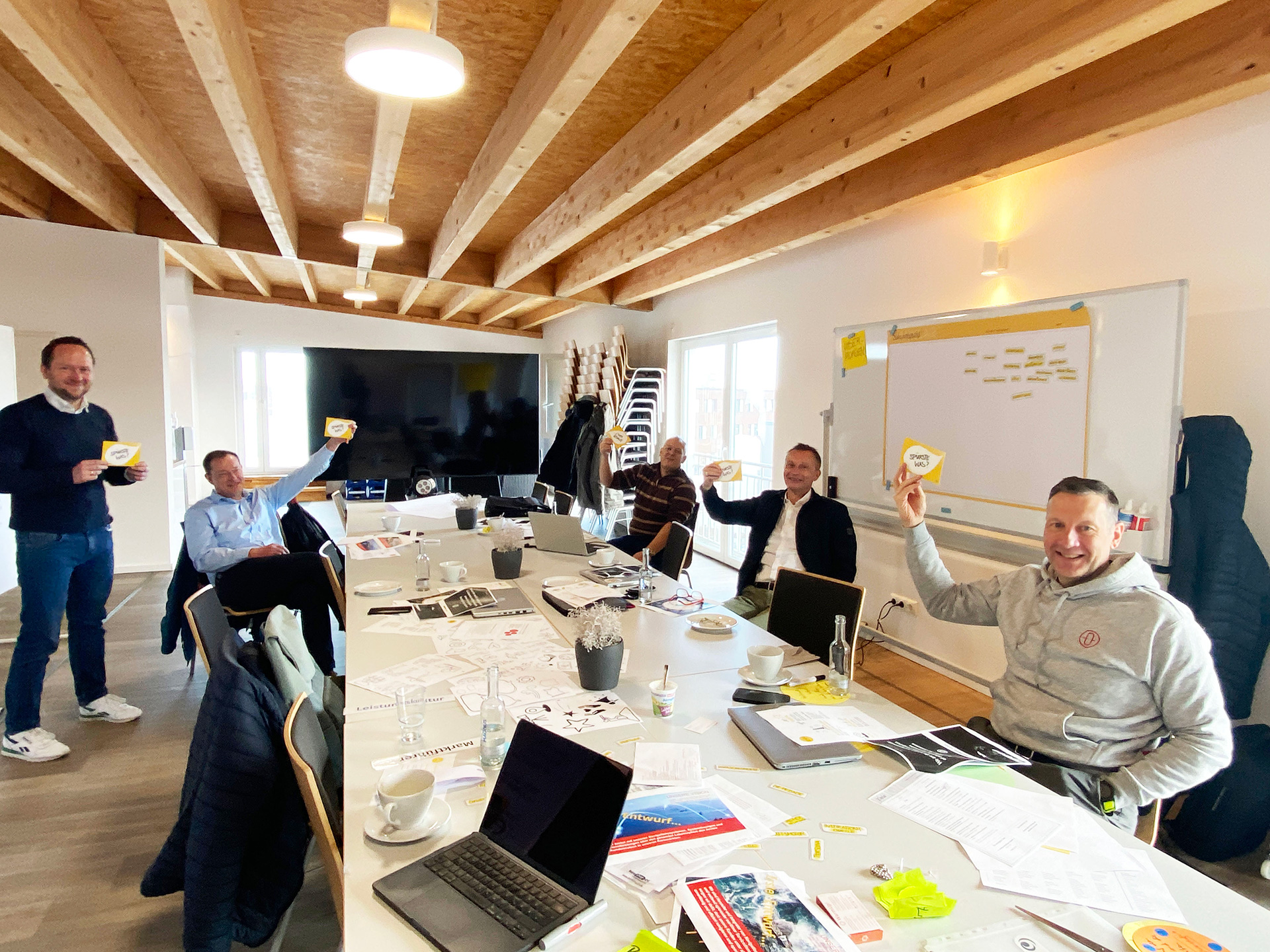 5 Teilnehmer im Zukunftsbild-Workshop an großem Tisch mit bunten Moderationsmaterialien